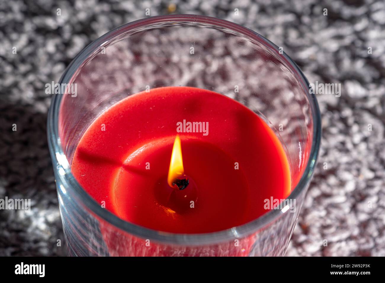 Rote Wachskerze mit brennender Flamme Stockfoto