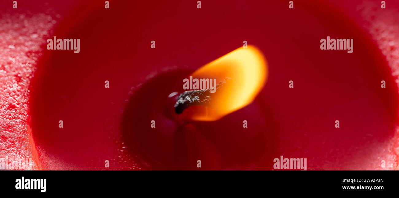 Rote Wachskerze mit brennender Flamme Stockfoto