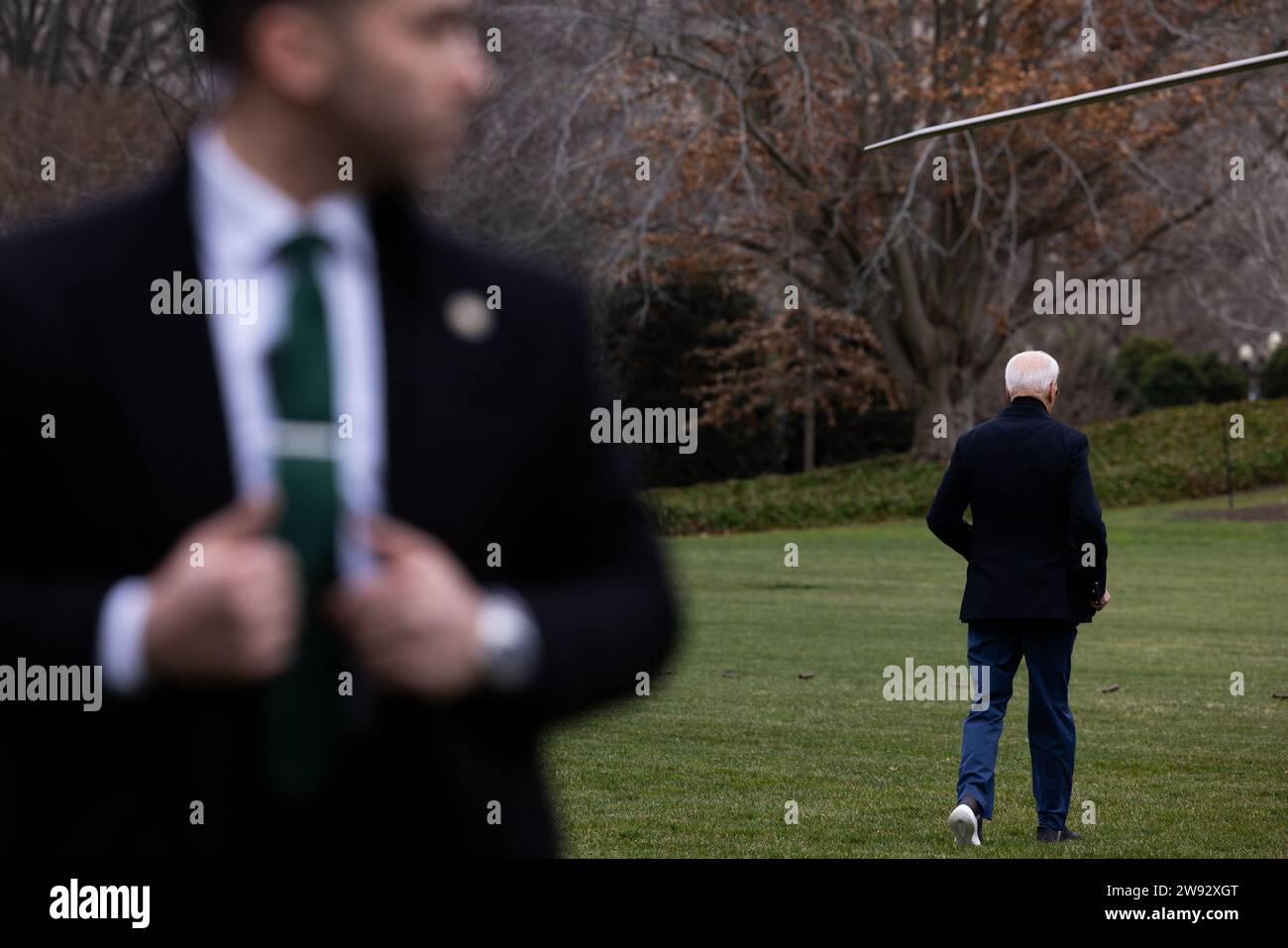 Washington, Usa. Dezember 2023. Ein Secret Service Agent beobachtet, wie Präsident Joe Biden am Samstag, 23. Dezember 2023, in Washington, DC, zur Marine One auf dem Südrasen des Weißen Hauses geht. Foto: Julia Nikhinson/UPI Credit: UPI/Alamy Live News Stockfoto