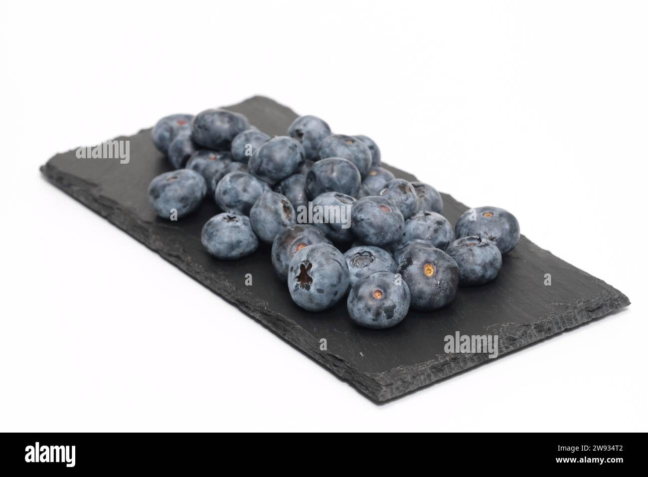 Heidelbeeren auf schwarzem Schiefer und isoliert auf weißem Hintergrund. Stockfoto