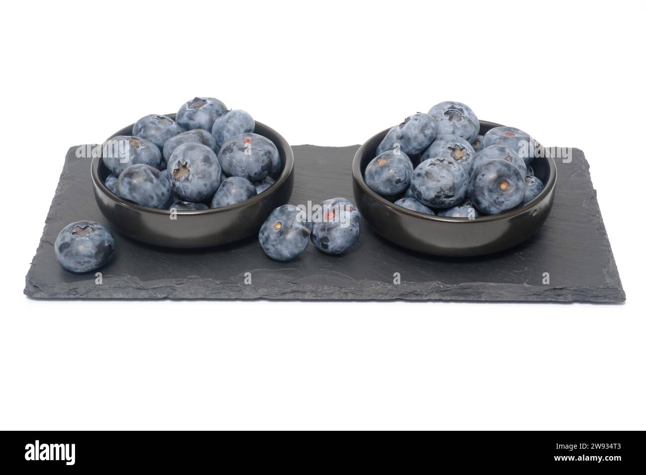 Heidelbeeren auf schwarzem Schiefer und isoliert auf weißem Hintergrund. Stockfoto