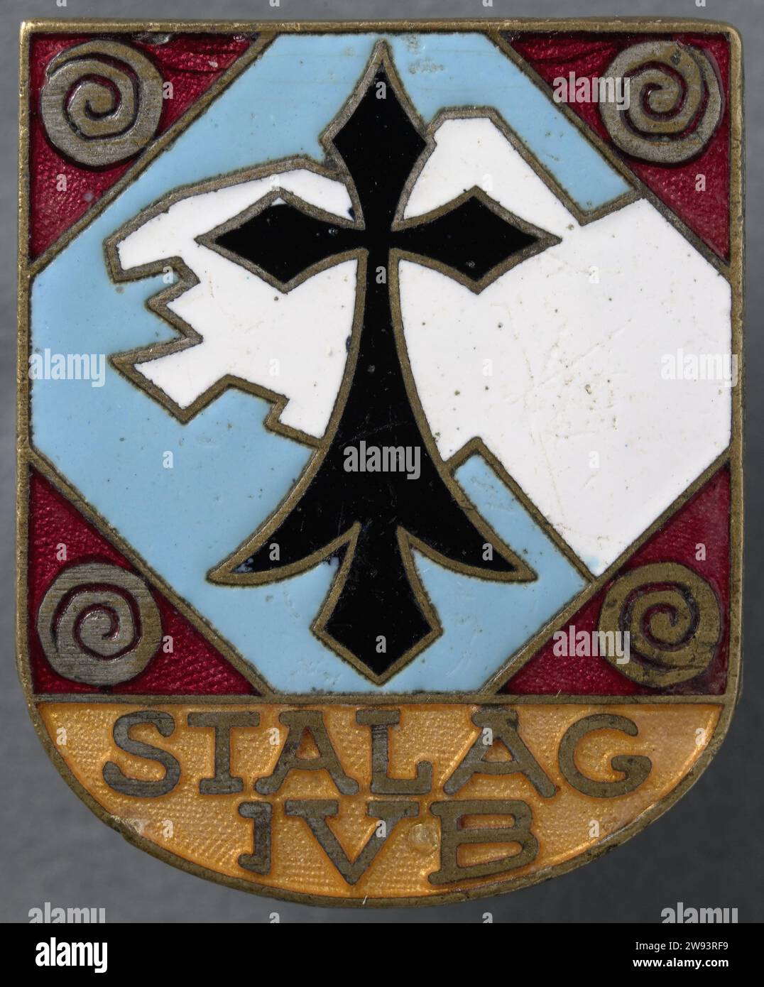 Wachstift in Stalag IVB in Mühlberg an der Elbe, 1942 - 1945 Metallschild mit Bild in Emaille, Farben: Schwarz, weiß, blau, rot und Gold. Unter der Inschrift in der Farbe Gold bis Gelb. Stift an der Rückseite abgebrochen. Wahrscheinlich von einem Wachmann im Stalag IVB in Mühlberg an der Elbe. Deutschland Metall. Kriegsgefangenenlager. Kriegsgefangener (nach der Schlacht) Mühlberg Stockfoto