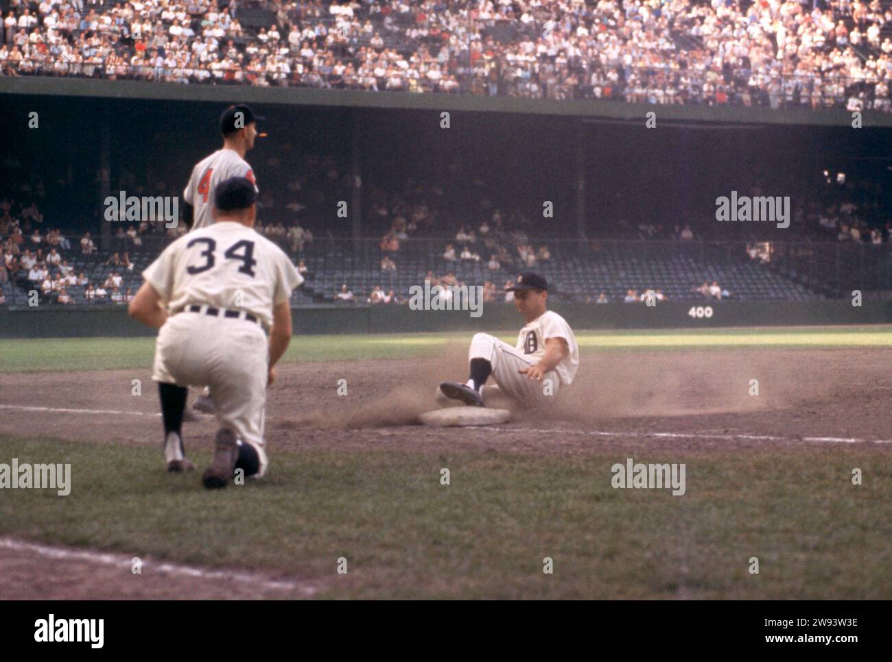 DETROIT, MI – 4. JULI: Der dritte Base-Trainer Billy Hitchcock #34 der Detroit Tigers zeigt Charlie Maxwell #4, als der dritte Baseman George Strickland #4 der Cleveland Indians während eines MLB-Spiels am 4. Juli 1959 im Briggs Stadium in Detroit, Michigan auf den Wurf wartet. (Foto von Hy Peskin) *** örtlicher Bildtitel *** Charlie Maxwell;Billy Hitchcock;Geroge Strickland Stockfoto