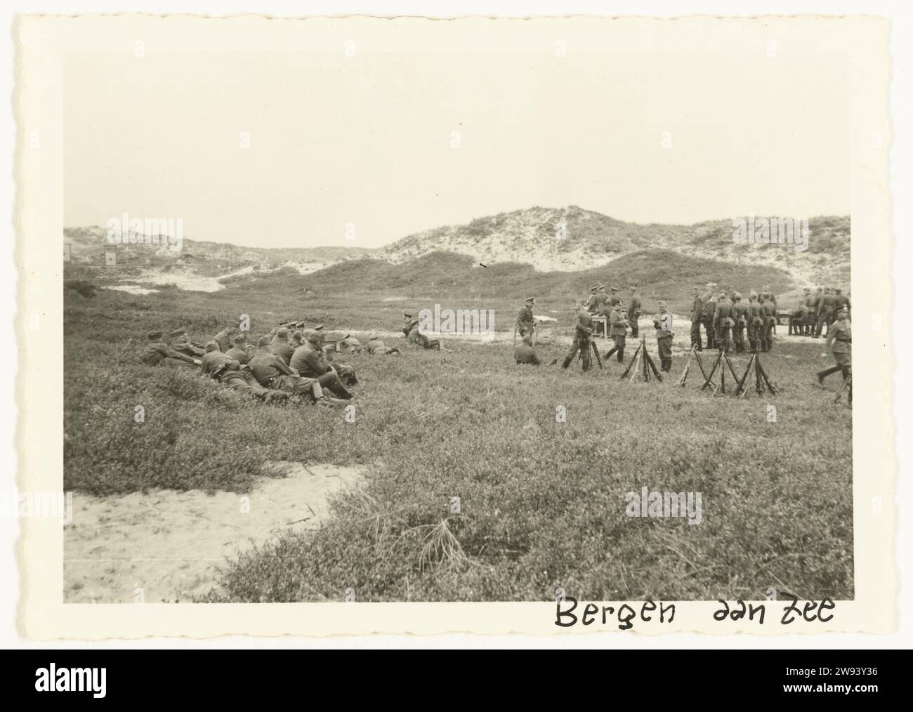 Ausübung der Wehrmacht, 1940 - 1941 Fotoruhe bei einer Ausübung der Wehrmacht in den Dünen. Einige der Männer sind auf dem Boden, andere stehen oder sitzen an Tischen. Die Waffen sind auf dem Boden gegeneinander. Bergen (Nordholland) fotografische Unterstützung Gelatine Silberdruck Besetzung  Krieg. Militärtraining Bergen (Nordholland) Stockfoto