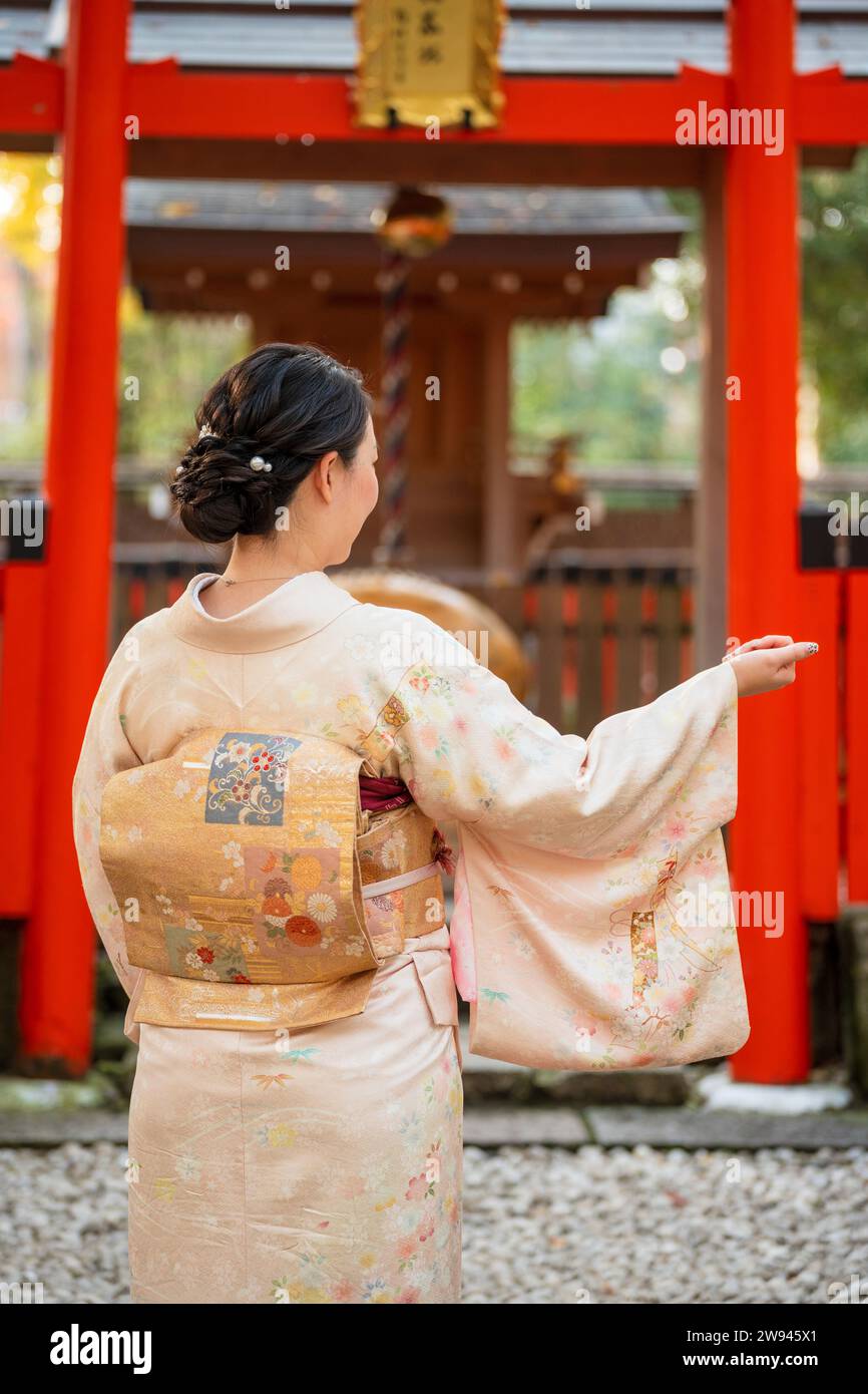 Japanische Kimono-Porträtfotografie. Kyoto, Japan. Traditioneller japanischer Schrein Torii im Hintergrund. Stockfoto