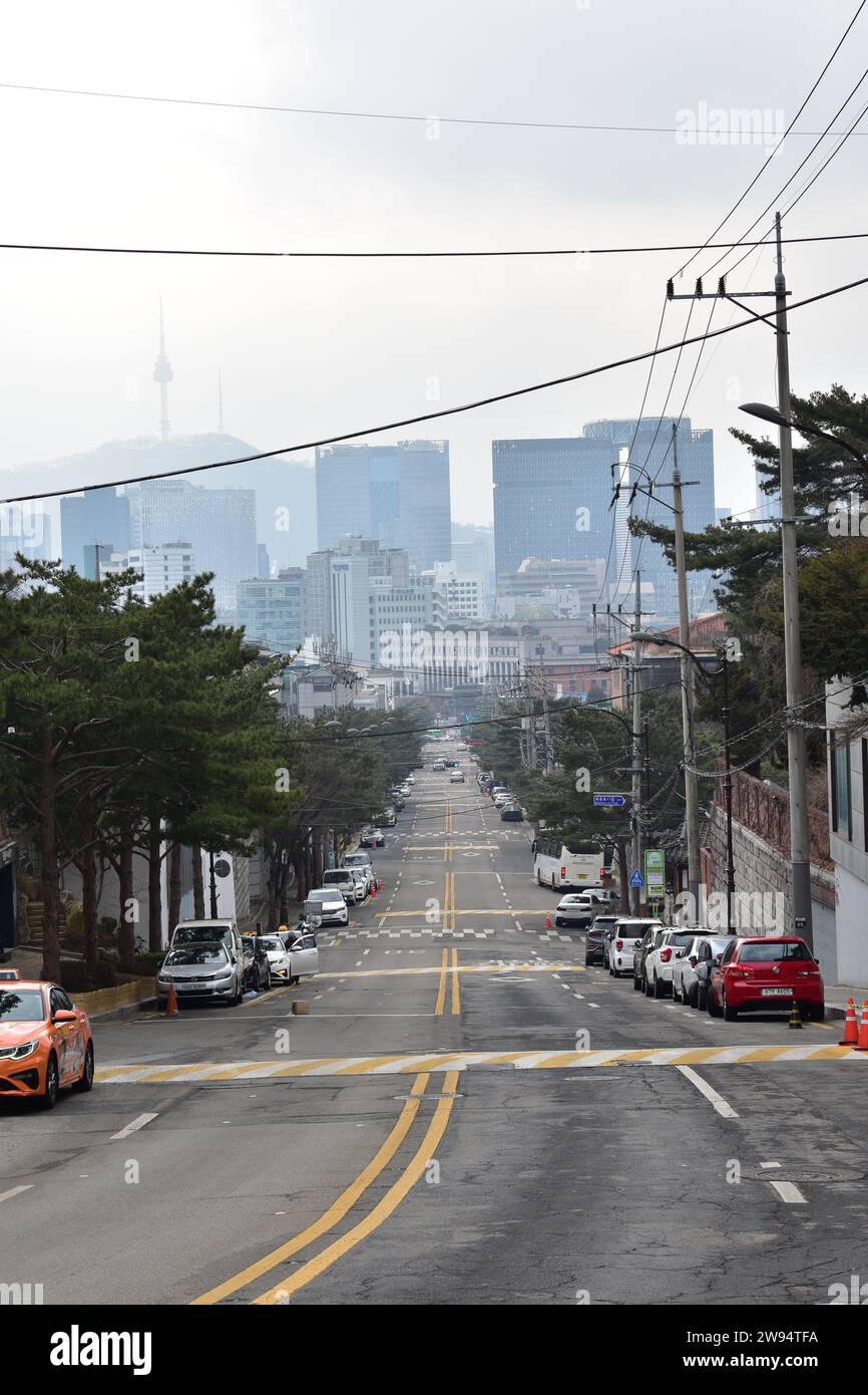 Blick bergab auf die Bukchon Road mit der Innenstadt von Seoul und der Skyline des North Seoul Tower im Hintergrund Stockfoto
