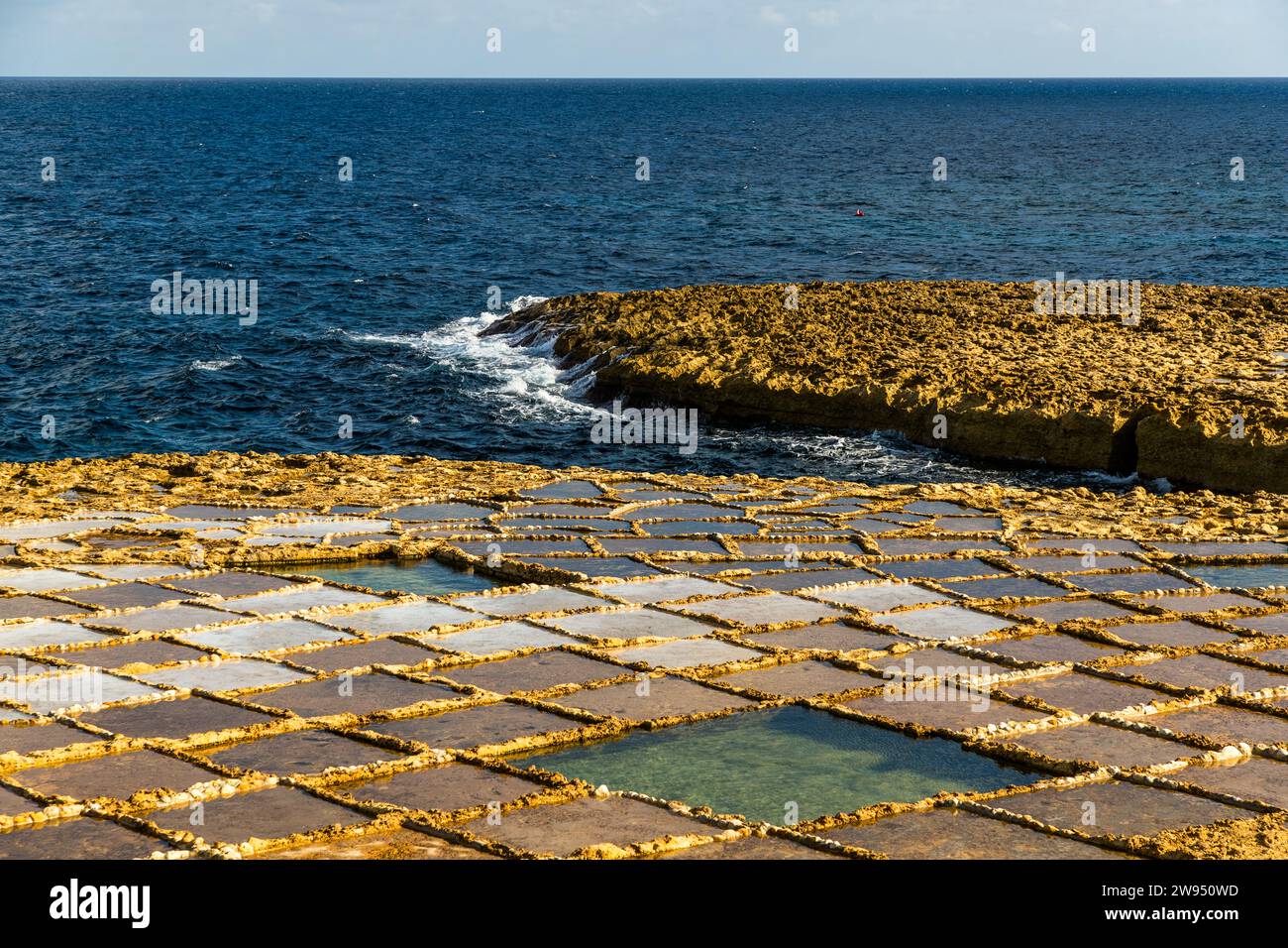 Bucht von Xwejni an der Nordküste von Gozo, wo die Familie Cini seit fünf Generationen Salz sammelt. Die Salinen erstrecken sich entlang der Küste, wo Meerwasser, Wind und Sonne die Bucht zu einem idealen Ort für die Salzgewinnung aus dem Mittelmeer machen. Leli Tal-Melh Salzladen in Xwejni in der Nähe von Marsalforn, Gozo, Malta Stockfoto