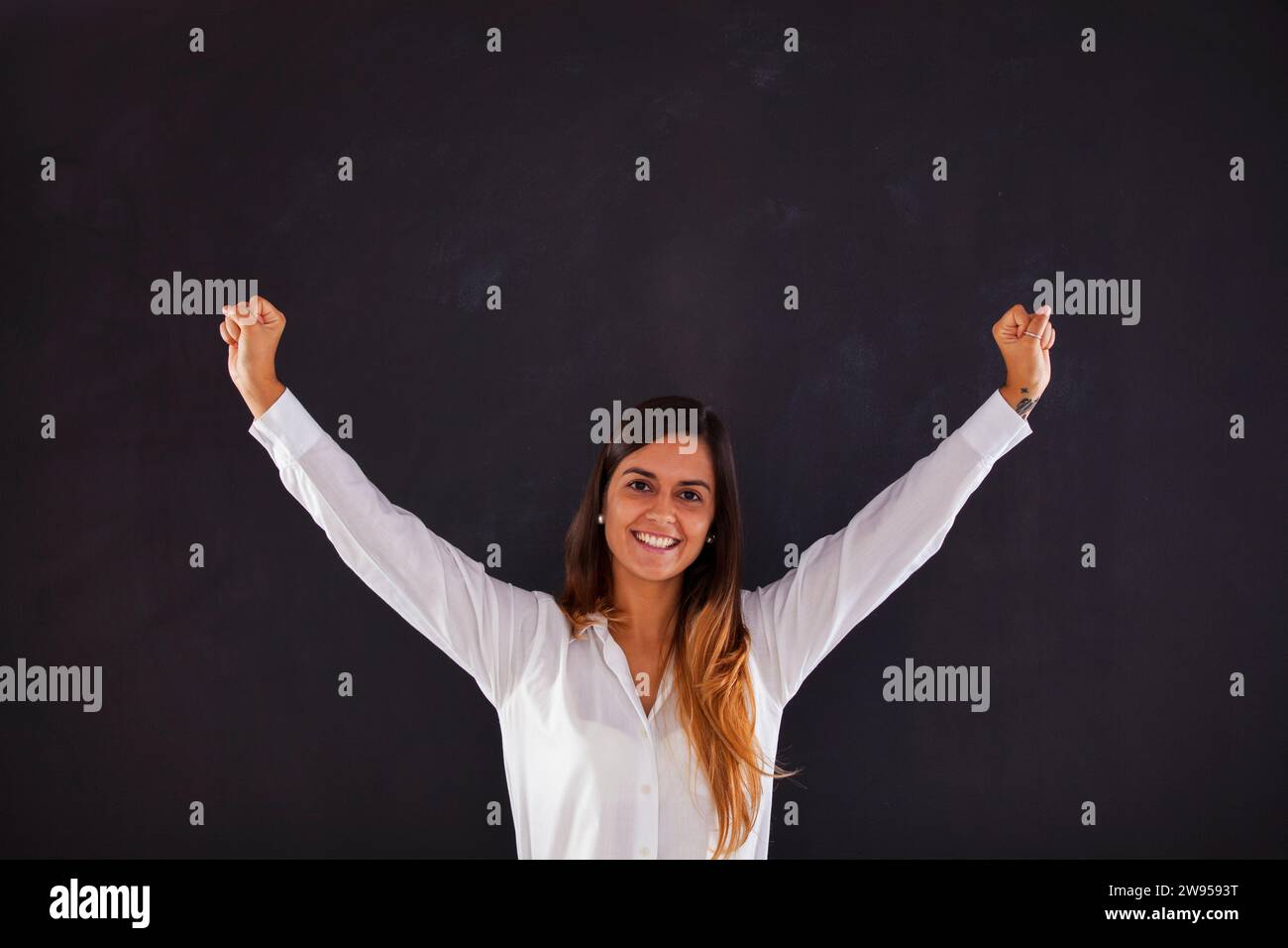Glückliche Frau neben der Tafel mit erhobenen Armen Stockfoto