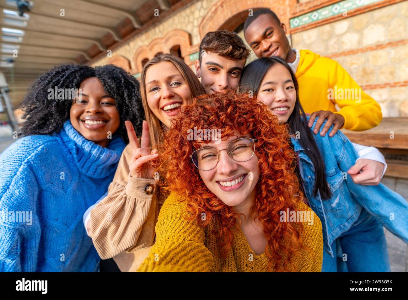 Verschiedene junge Freunde, die ein Selfie machen, lächelnd und mit Gesten erfolgreich in einem urbanen Raum Stockfoto