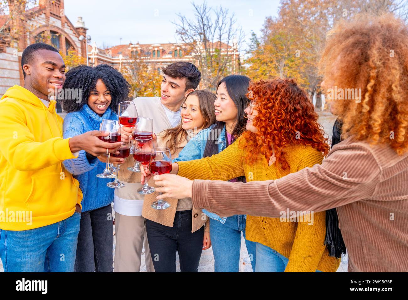 Vielfältige junge Leute stehen und toasten mit Rotwein auf der Straße Stockfoto