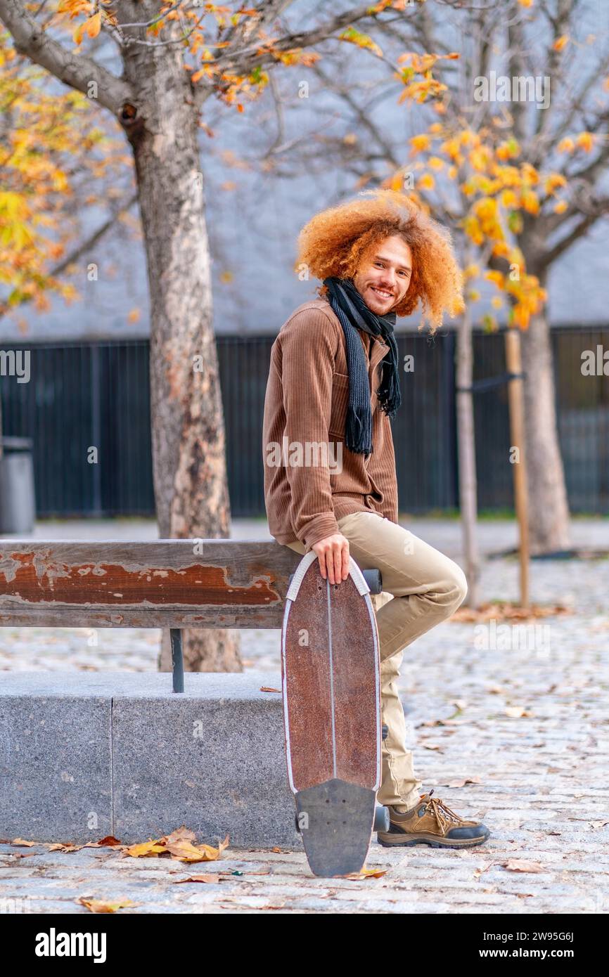 Vertikales Porträt der Seitenansicht eines alternativen erwachsenen Mannes mit Schlittschuhlaufen in einem Stadtpark im Herbst Stockfoto