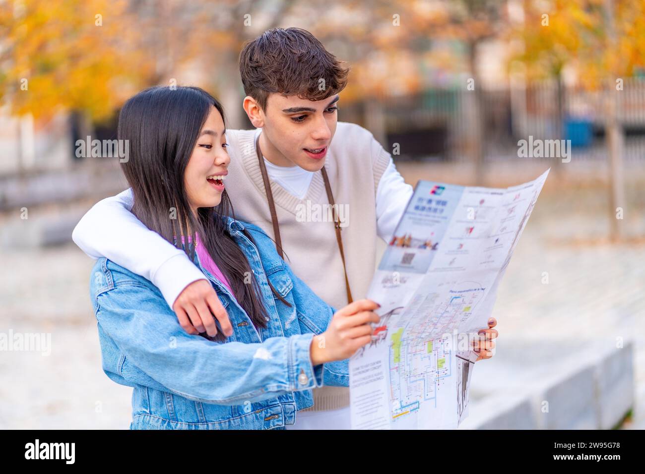 Ein multiethnisches junges Paar, das sich eine Karte ansieht, die auf der Stadt steht Stockfoto