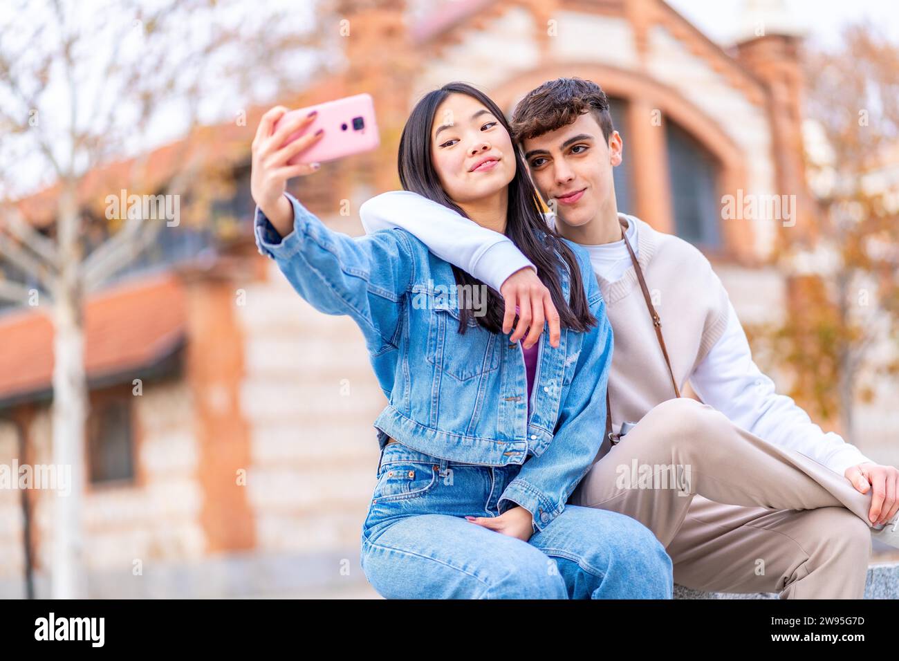 Multiethnisches Teenager-Paar, das ein Selfie macht und sich in einem Stadtpark umschließt Stockfoto