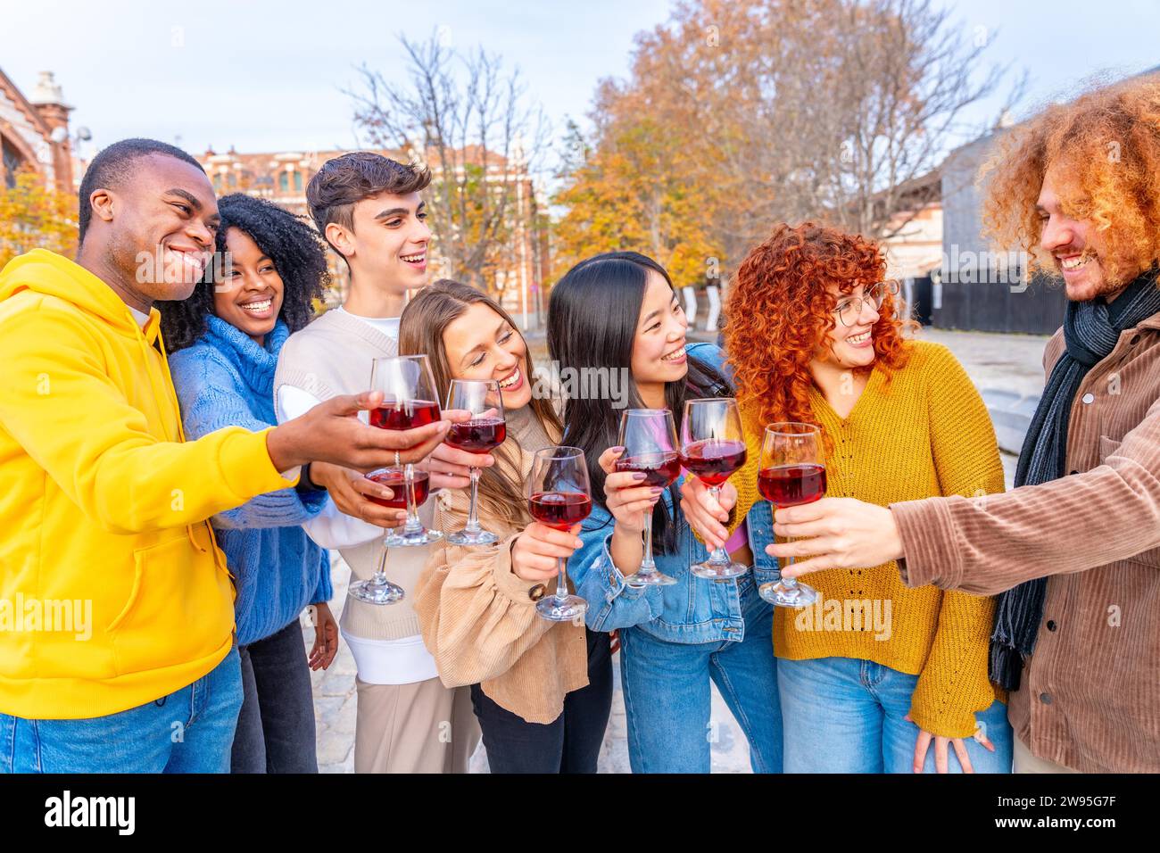 Multiethnische Freunde lächeln und trinken mit Rotwein auf der Straße Stockfoto