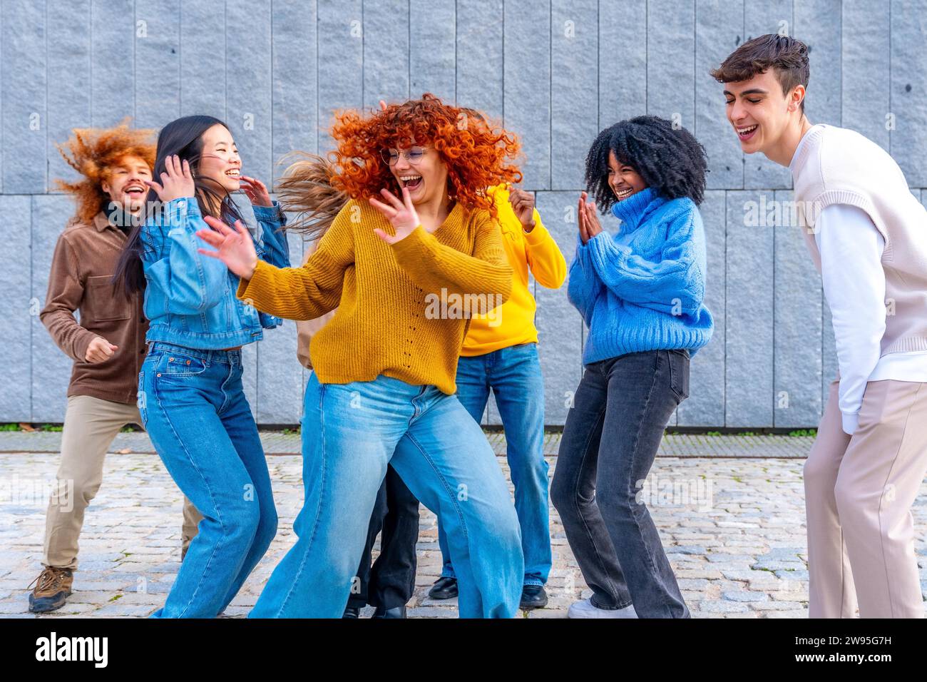 Frontalansicht eines glücklichen Mädchens, das mit einer Gruppe von Freunden in der Stadt tanzt Stockfoto