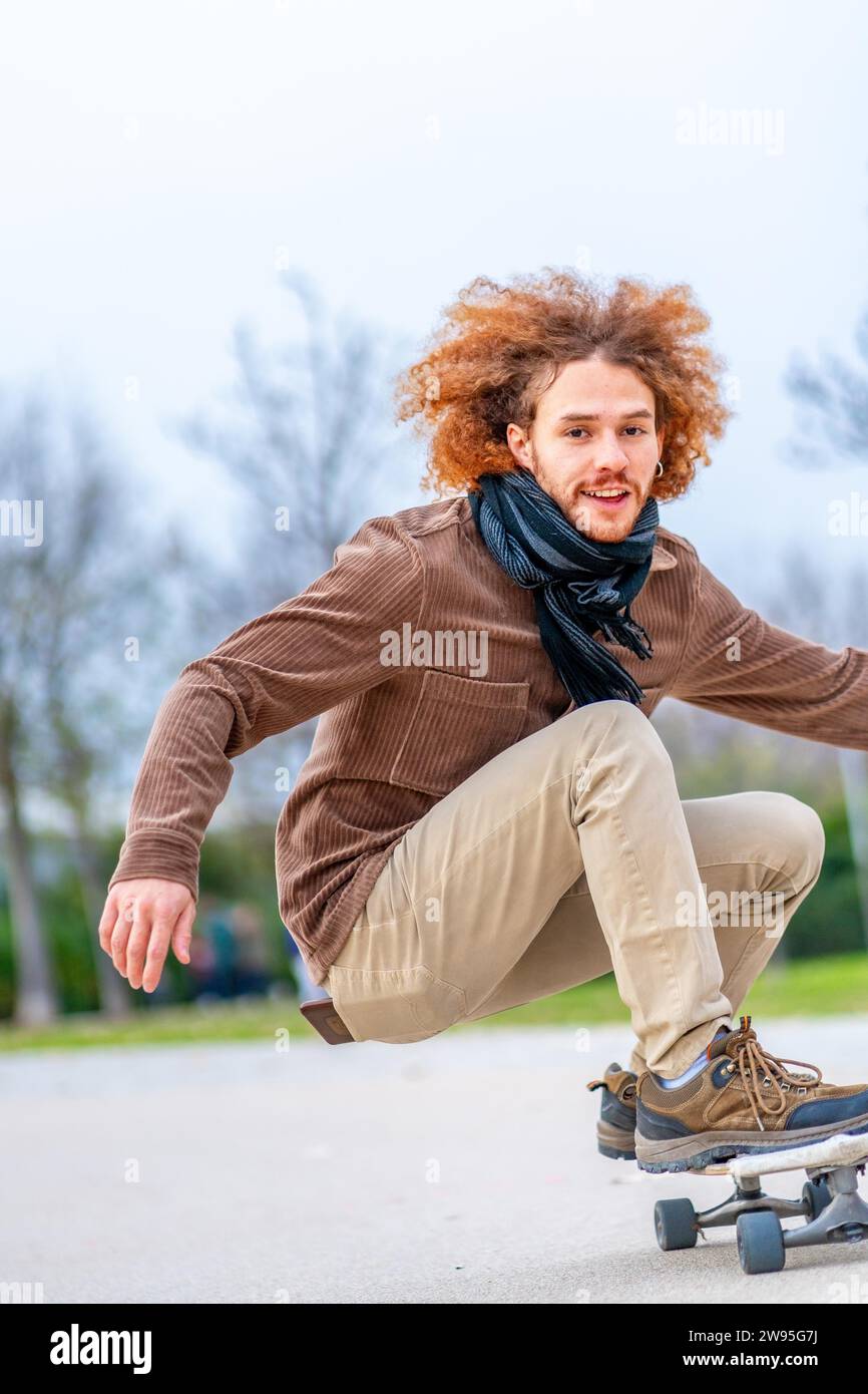 Vertikales Foto mit Kopierraum eines glücklichen jungen Mannes, der in einem Park Skateboarden fährt Stockfoto