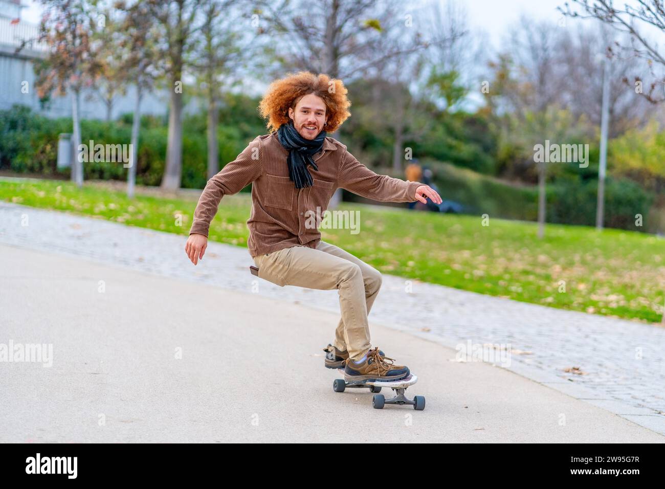 Foto mit Bewegungs- und Kopierraum eines glücklichen jungen Mannes, der in einem urbanen Park Skateboarden fährt Stockfoto
