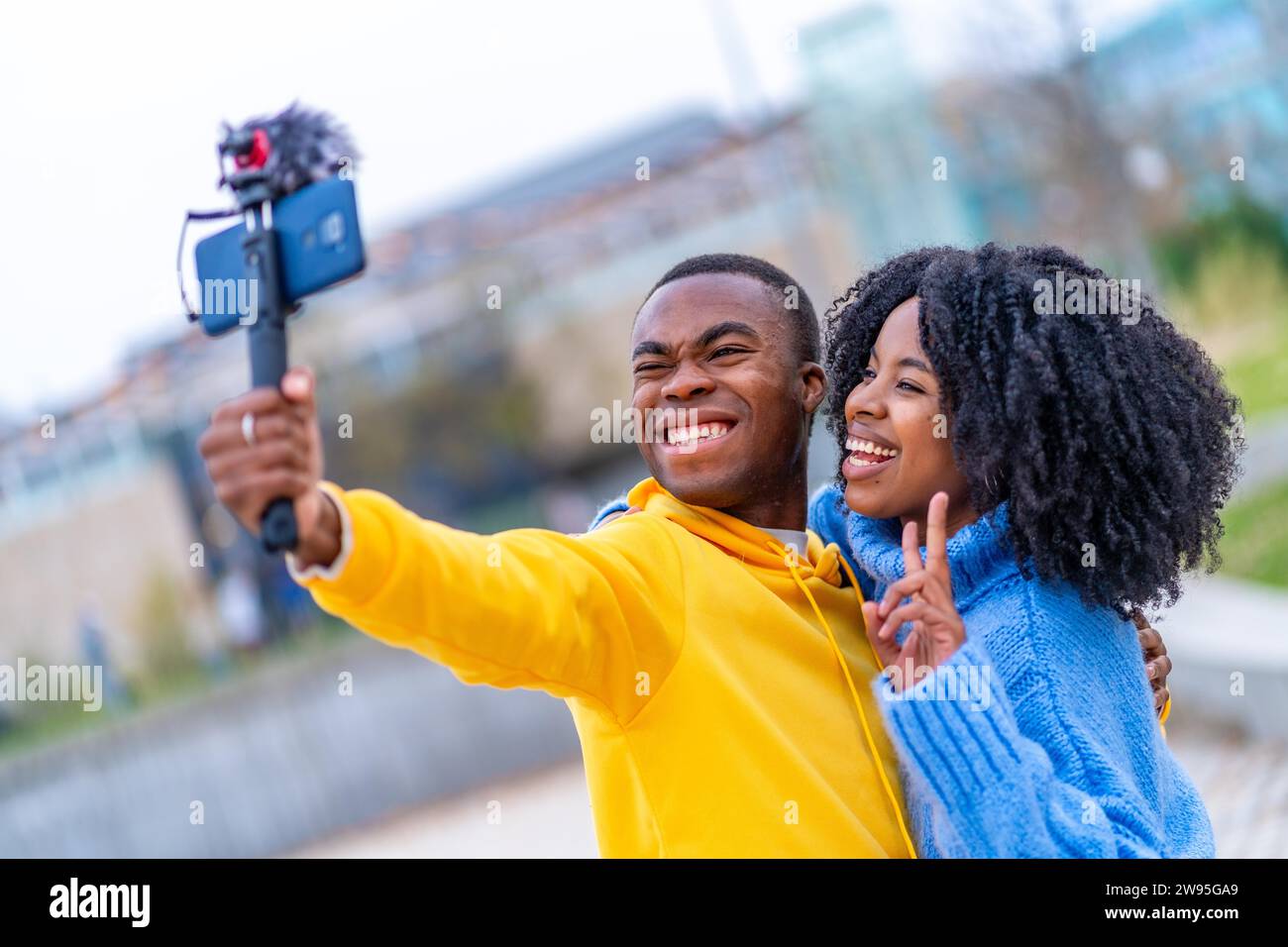 Afrikanische Jugendliche lächeln und mit Gesten den Sieg beim Aufnehmen eines Videos auf der Straße Stockfoto