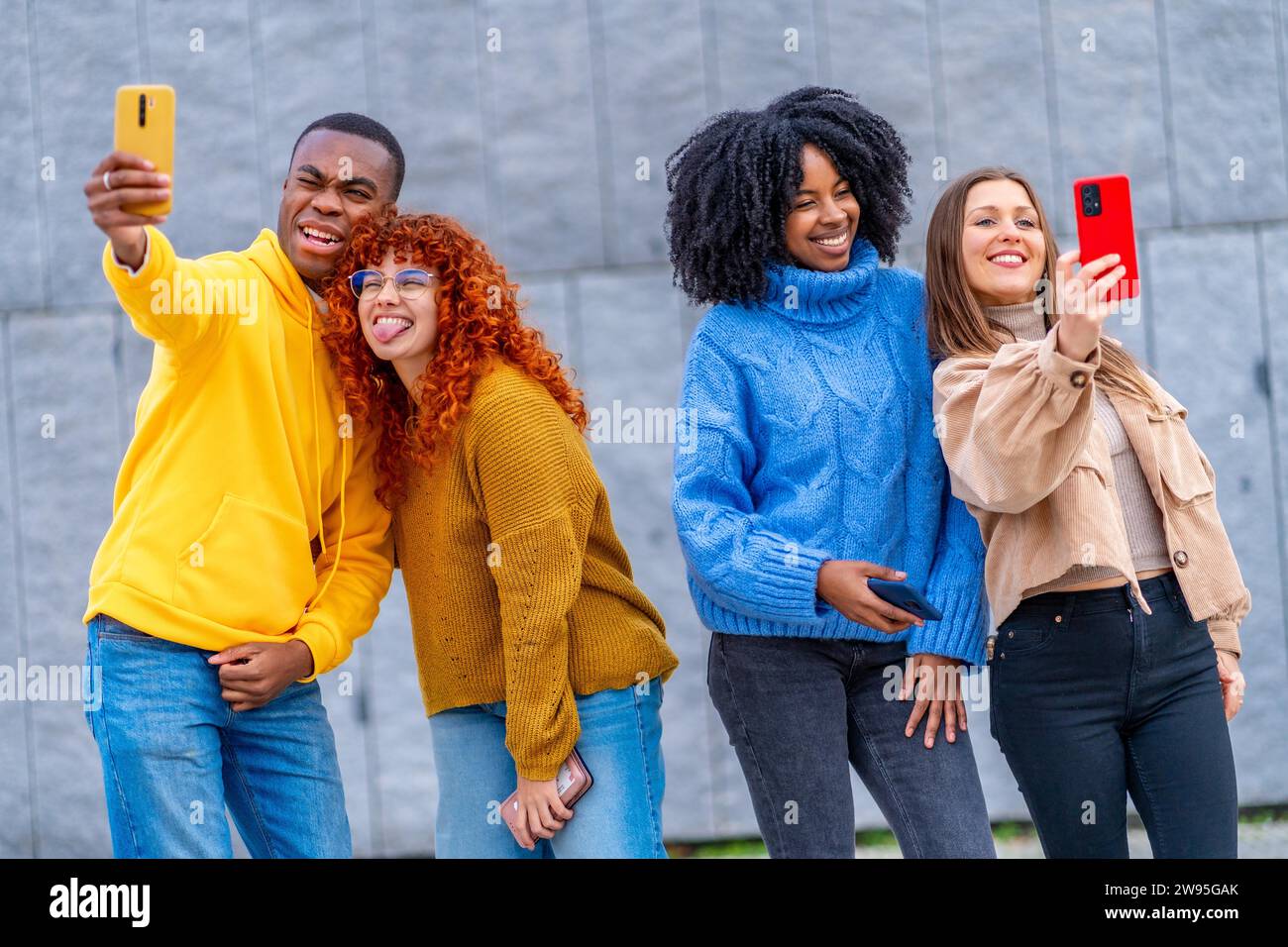 Multiethnische Jugendliche, die Selfies machen, stehen in einem städtischen Raum Stockfoto