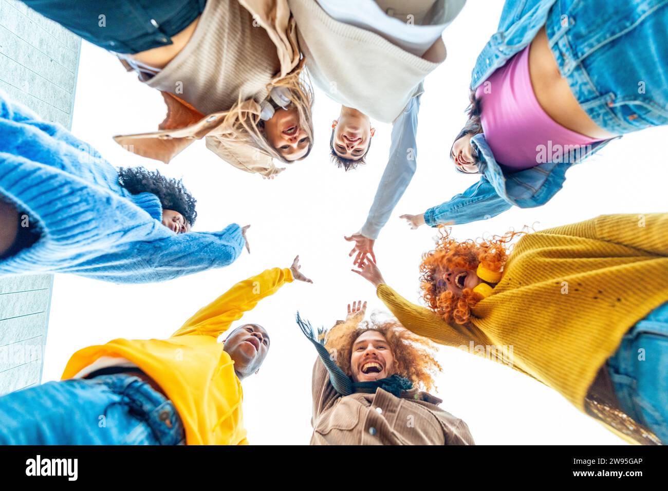 Niedriges Foto einer lächelnden multiethnischen Gruppe, die sich zusammenschließt und die Hände hebt Stockfoto