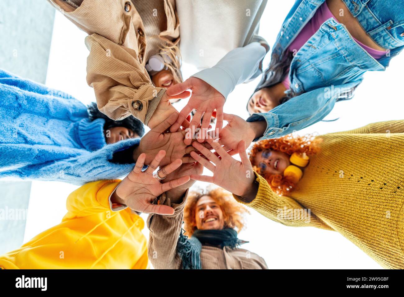 Tiefwinkelansicht einer Gruppe unterschiedlicher junger Menschen, die sich im Kreis zusammenschließen Stockfoto