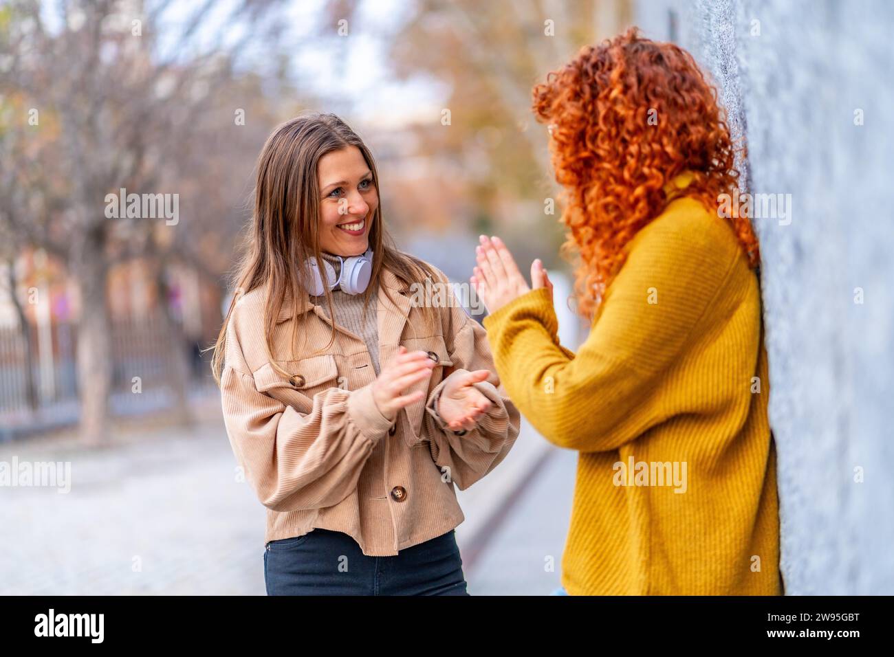 Zwei moderne weibliche Friends, die auf der Straße lächeln und reden Stockfoto