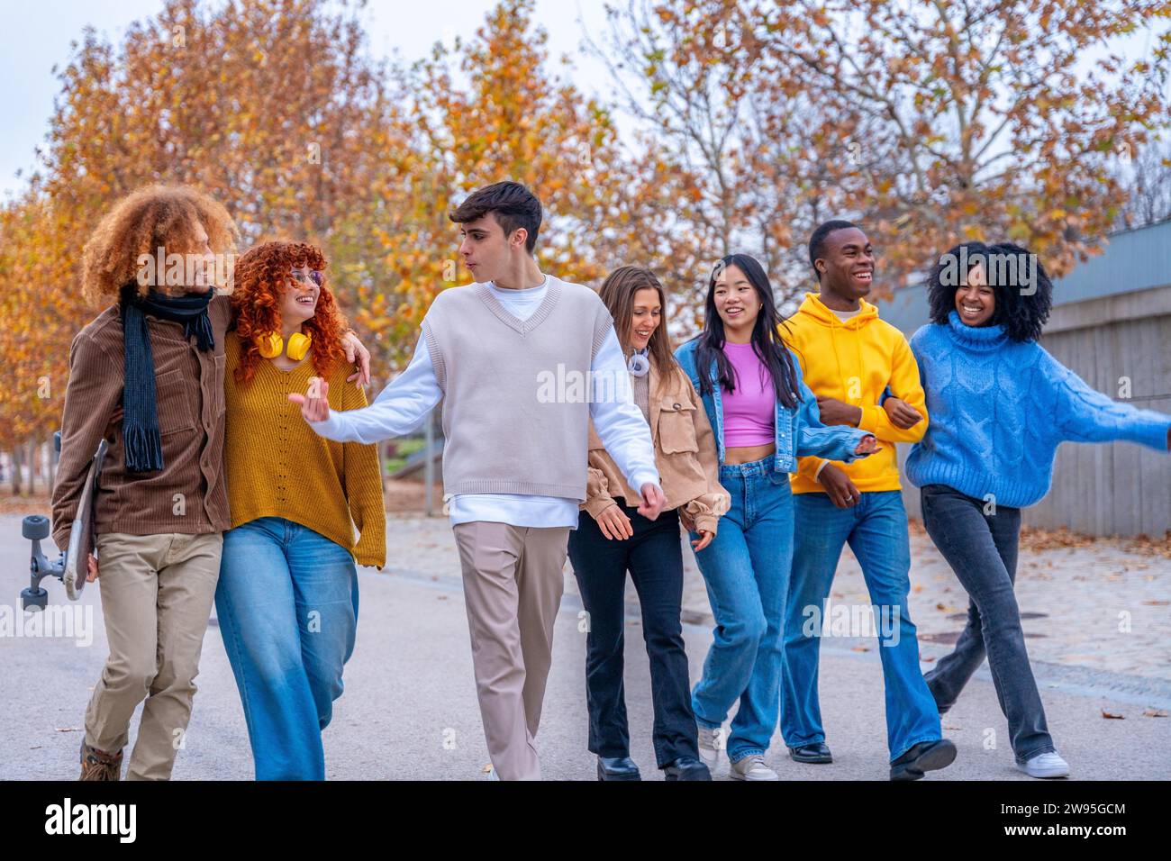 Multiethnische Studenten spazieren über den Campus, plaudern und umarmen Stockfoto