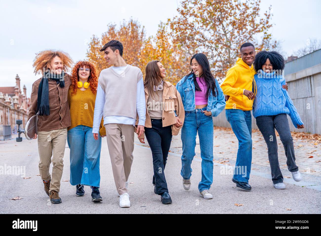 Multiethnische Freunde lächeln, reden und gehen in einer Stadtstraße in der Schlange Stockfoto