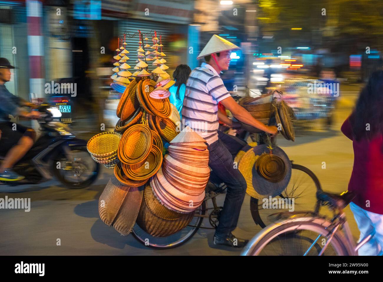 Korb- und Hutverkäufer auf dem Fahrrad in der belebten Straße, Hanoi, Vietnam Stockfoto