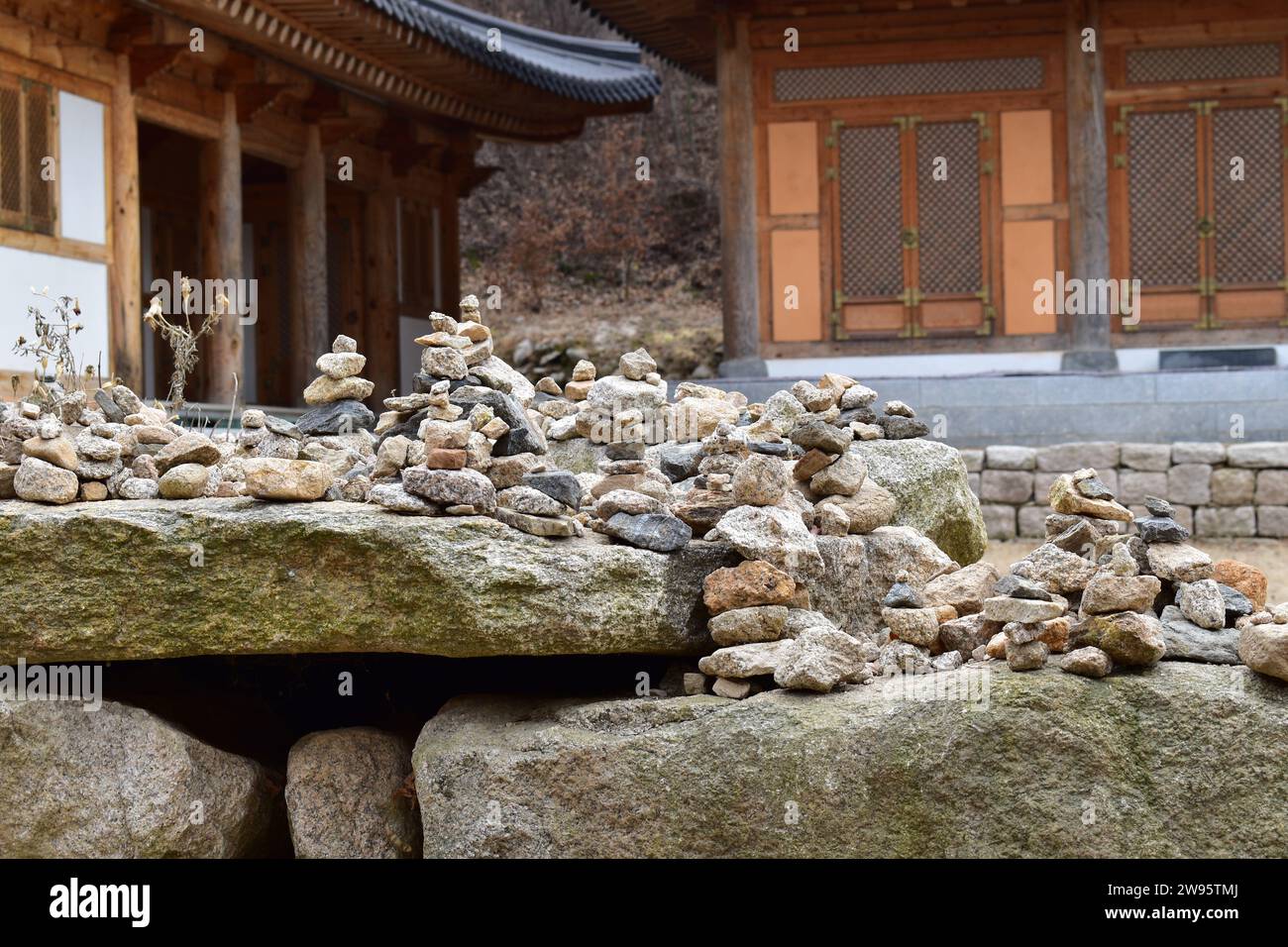 Kleine Türme aus Kieseln und Felsen, die von vorbeifahrenden Wanderern mit historischen koreanischen Gebäuden im Hintergrund im Bukhansan-Nationalpark gebaut wurden Stockfoto