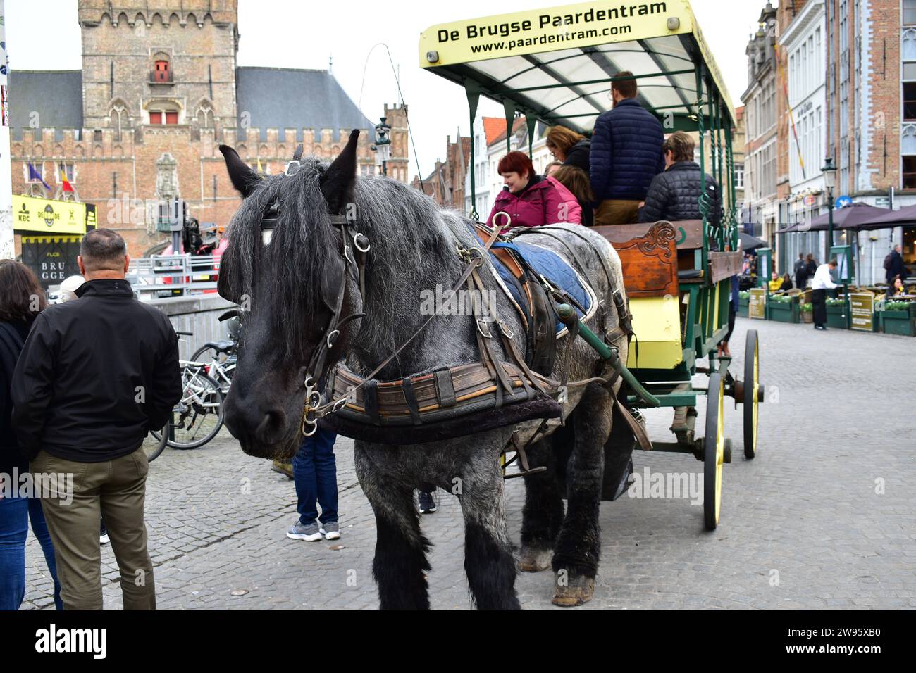 Touristen auf einer Tour „Brügge Reiter“ in einer Holzkutsche, die von einem Pferd gezogen wird, auf dem Grand Place im mittelalterlichen Stadtzentrum von Brügge Stockfoto