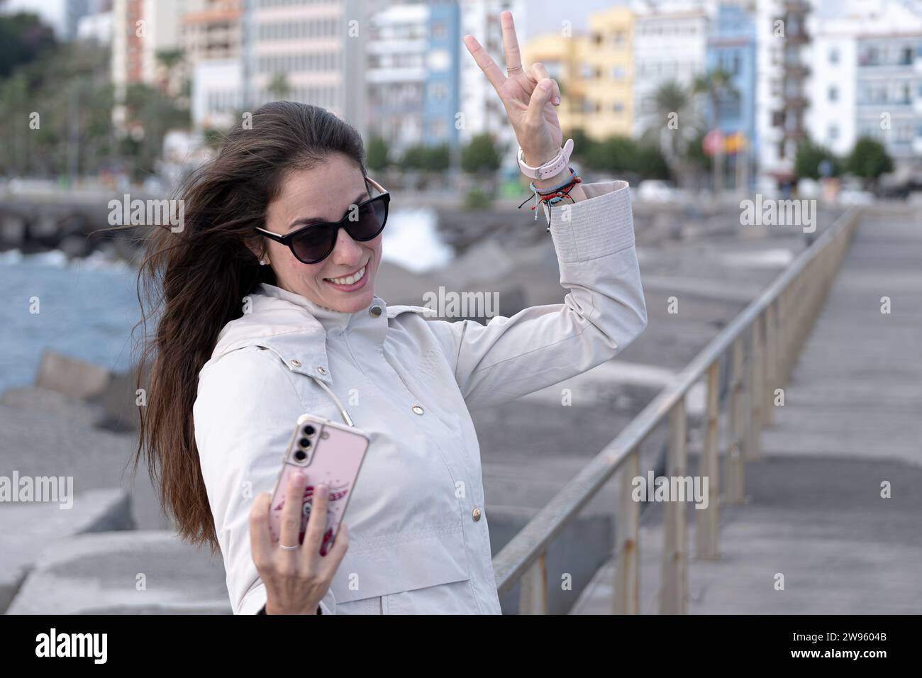 Ein weißes Mädchen macht ein Selfie und macht das Siegessymbol mit ihren Fingern. Stockfoto