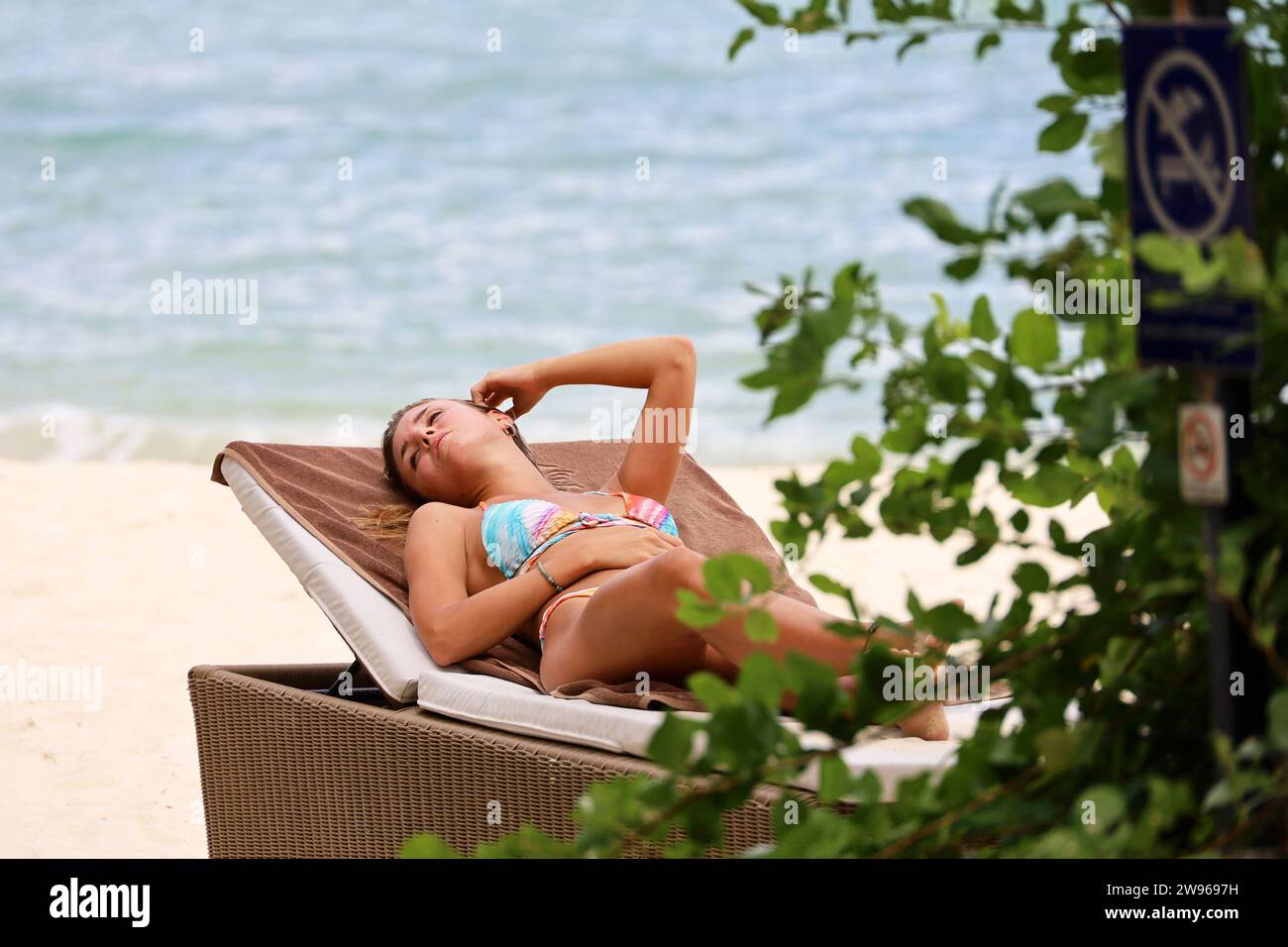 Frau, die sich im Liegestuhl bräunt. Strandurlaub im Seebad Stockfoto