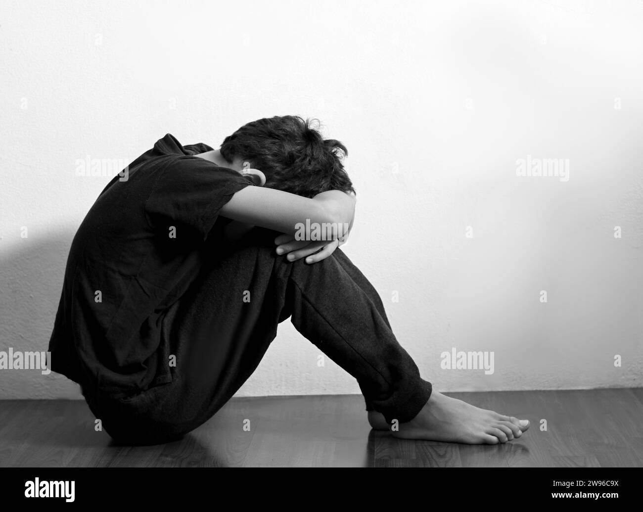 Junge betet in Armut auf dem Boden Stockbild ohne Hilfe allein und ganz allein auf weißem Hintergrund Stockfoto Stockfoto