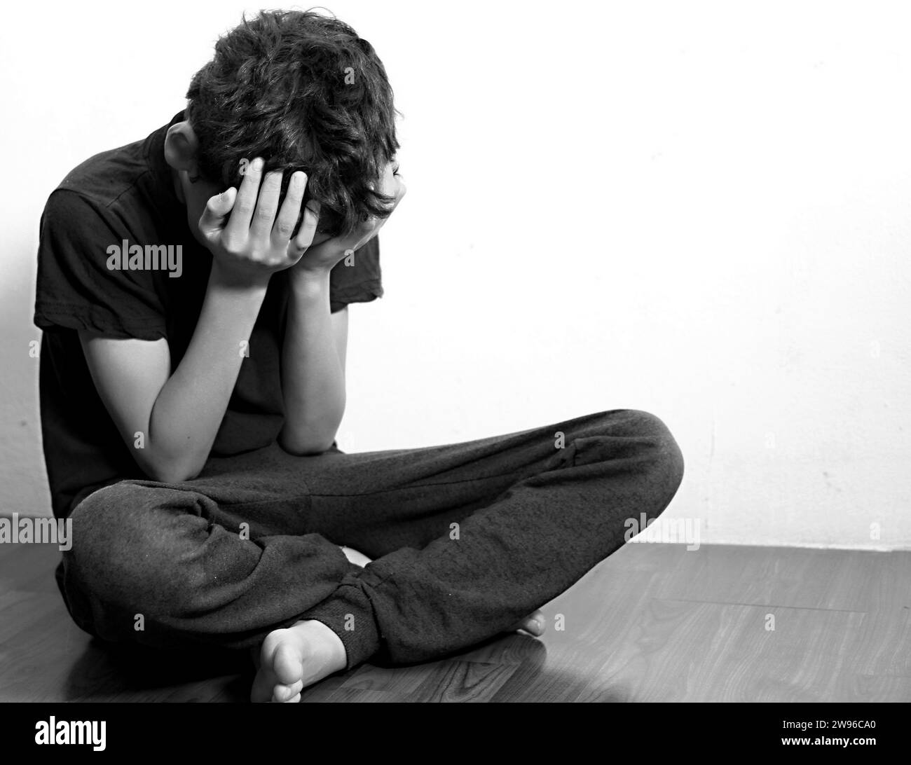 Junge betet in Armut auf dem Boden Stockbild ohne Hilfe allein und ganz allein auf weißem Hintergrund Stockfoto Stockfoto