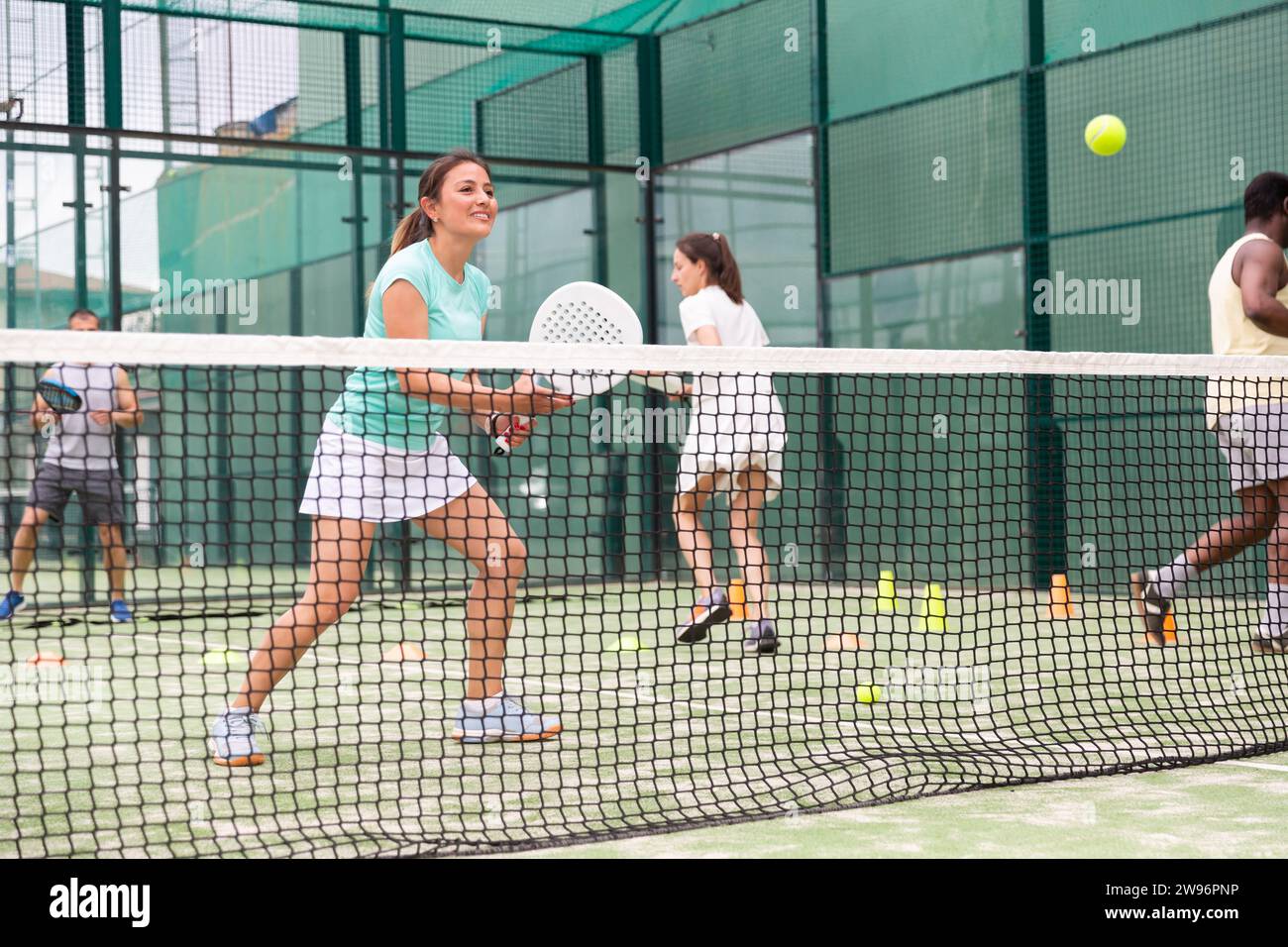 Porträt einer fröhlichen Tennisspielerin beim Gruppentraining auf dem Platz Stockfoto