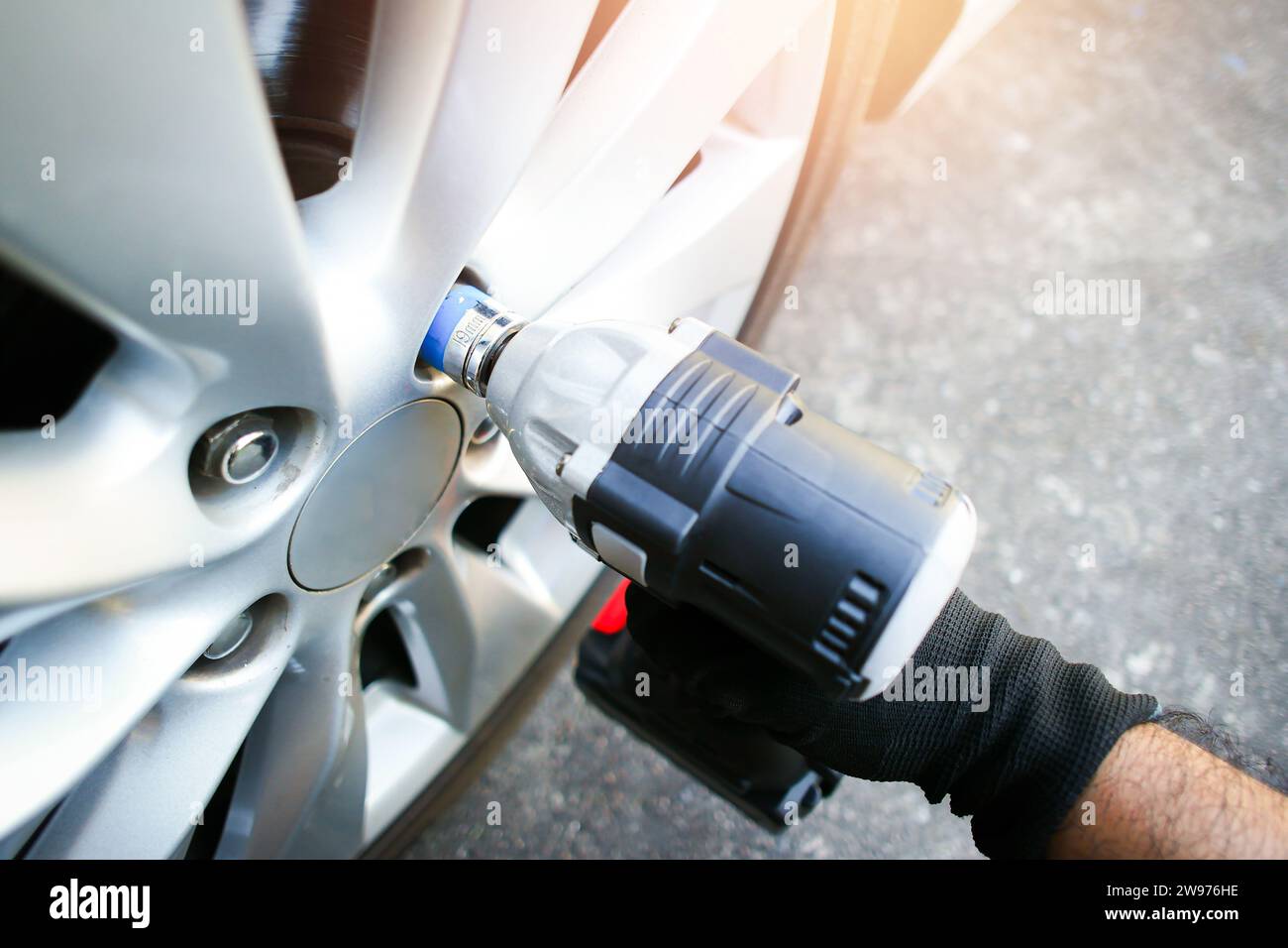 Automechaniker verwenden Akku-Schlagschrauber zum Entfernen der Radmuttern des Fahrzeugs, Servicekonzept für die Fahrzeugverfälschung Stockfoto