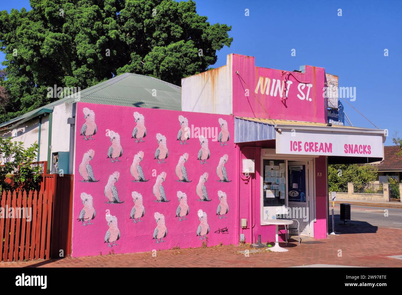 Perth: Farbenfroher alter rosa Feinkostladen mit Galah-Kakadu-Wandkunst in der Mint Street, East Victoria Park, Perth, Western Australia Stockfoto