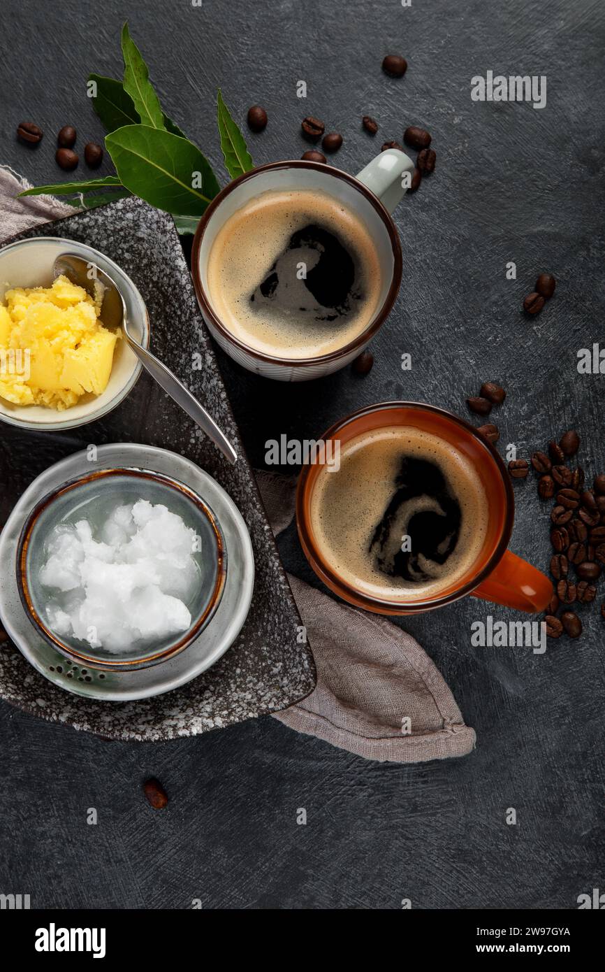 Kugelsicherer Keto-Kaffee. Ketogene Diät. Heißes Trocknen mit Kokosöl und Ghee-Butter auf dunklem Hintergrund. Draufsicht Stockfoto