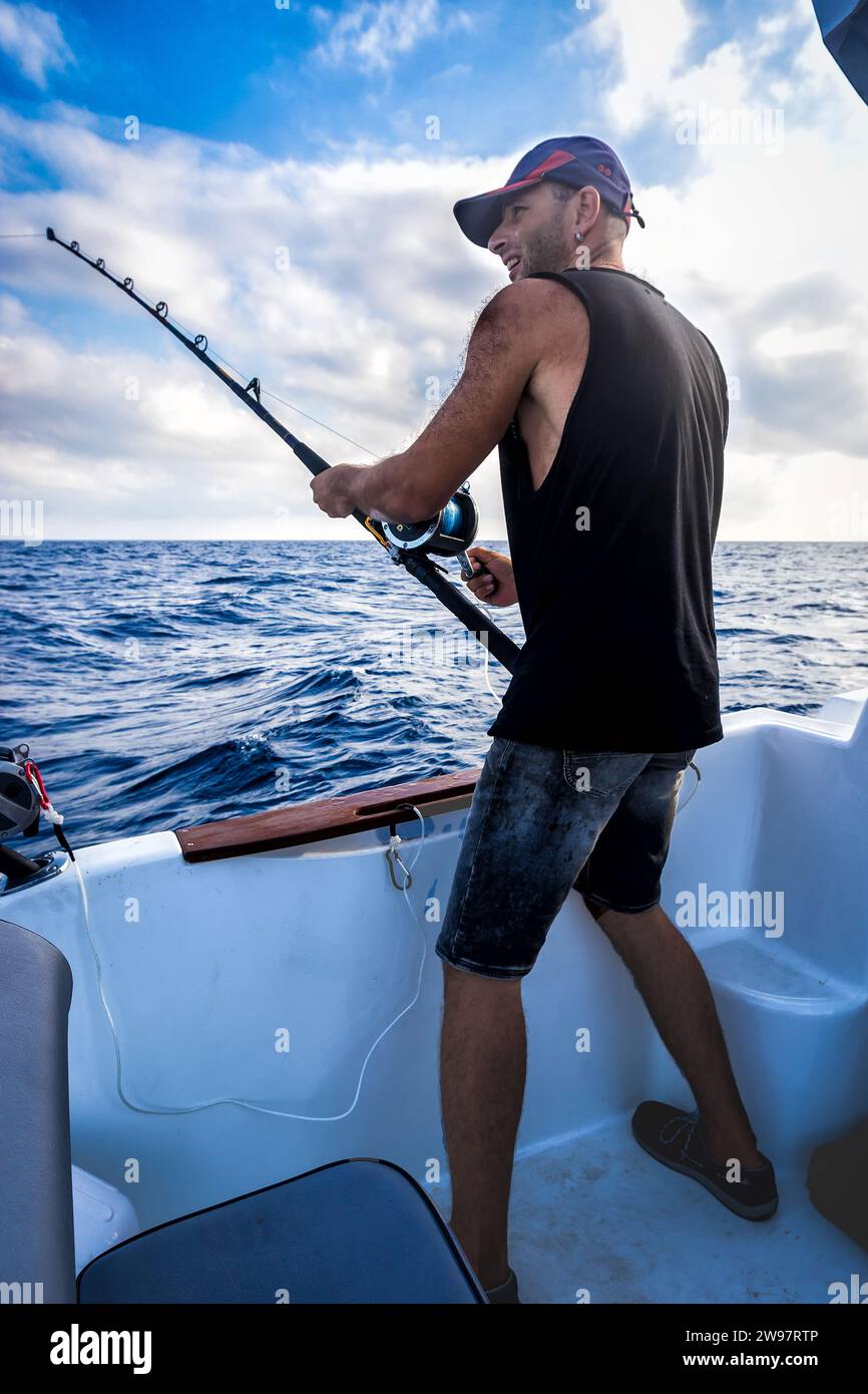 Der junge Mann in einer Baseball Cap an Bord des Schiffes im Laufe der Fischerei vor dem Hintergrund des blauen Meeres. Stockfoto