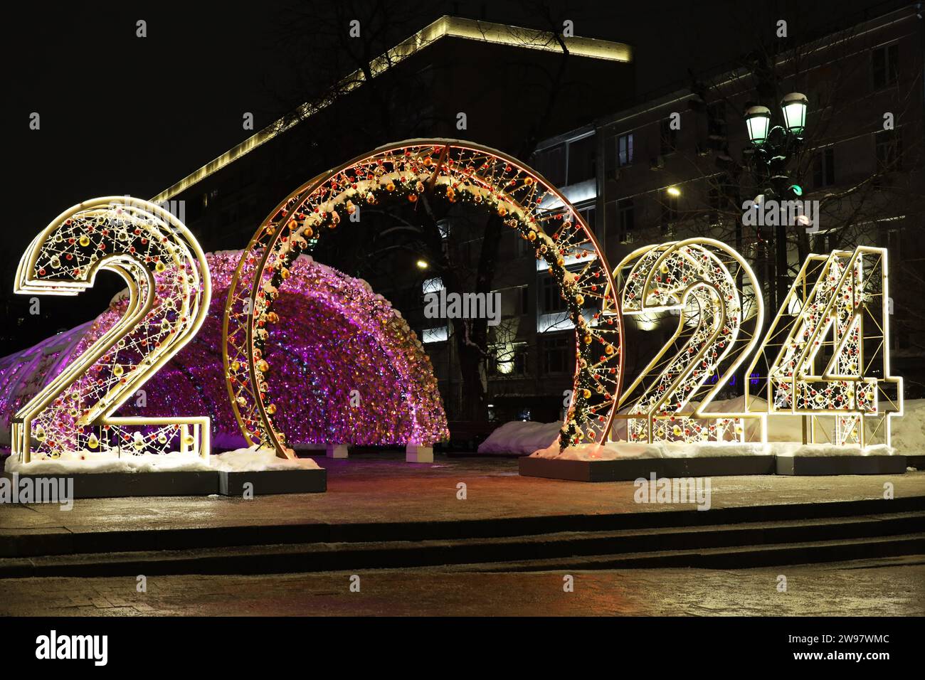 Neujahrsdekoration auf einer nächtlichen Stadtstraße mit großen Zahlen 2024. Festliche Beleuchtung, Weihnachtsfeier Stockfoto