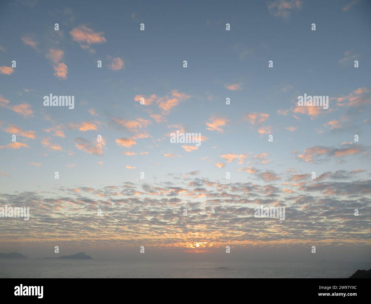 Ein atemberaubender Blick auf eine malerische Küste, bei Sonnenuntergang, der das ruhige Wasser unter sich erleuchtet Stockfoto