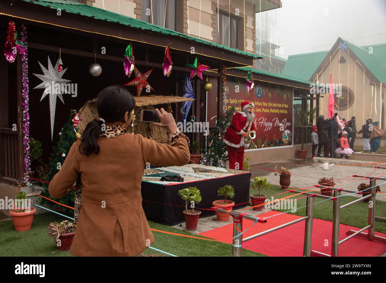 Srinagar, Kaschmir, Indien. Dezember 2023. Ein Mädchen wird gesehen, wie er vor dem Weihnachtsfest in Srinagar Fotos von dem Weihnachtsmann macht. (Kreditbild: © Adil Abbas/ZUMA Press Wire) NUR REDAKTIONELLE VERWENDUNG! Nicht für kommerzielle ZWECKE! Stockfoto