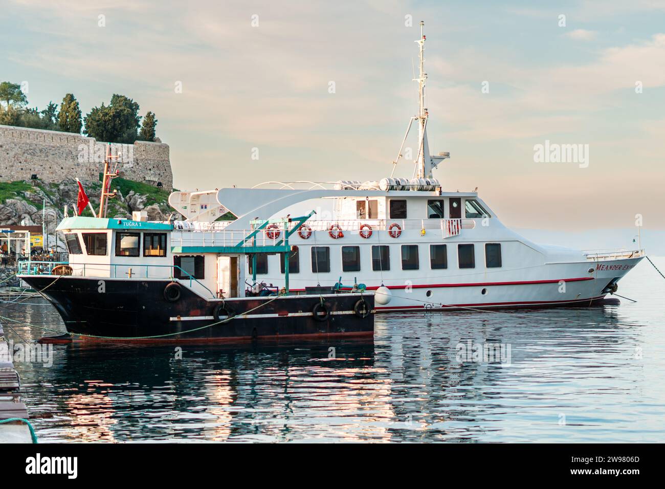 Ein kleines Boot legt im ruhigen blauen Wasser am Rand einer felsigen Steinmauer an. Stockfoto