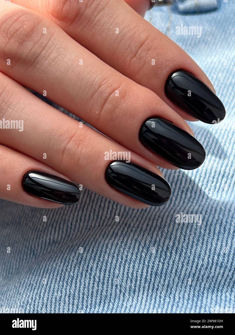 Eine Nahaufnahme eines Weibchens mit sorgfältig gepflegten schwarzen Fingernägeln Stockfoto