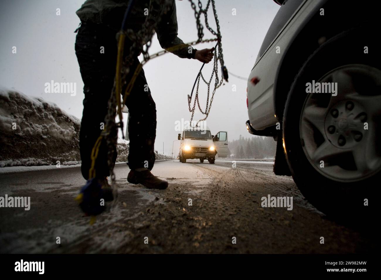 Ein Mann versucht, Ketten an sein Fahrzeug zu legen, im Schnee, Reno, Nevada. Stockfoto