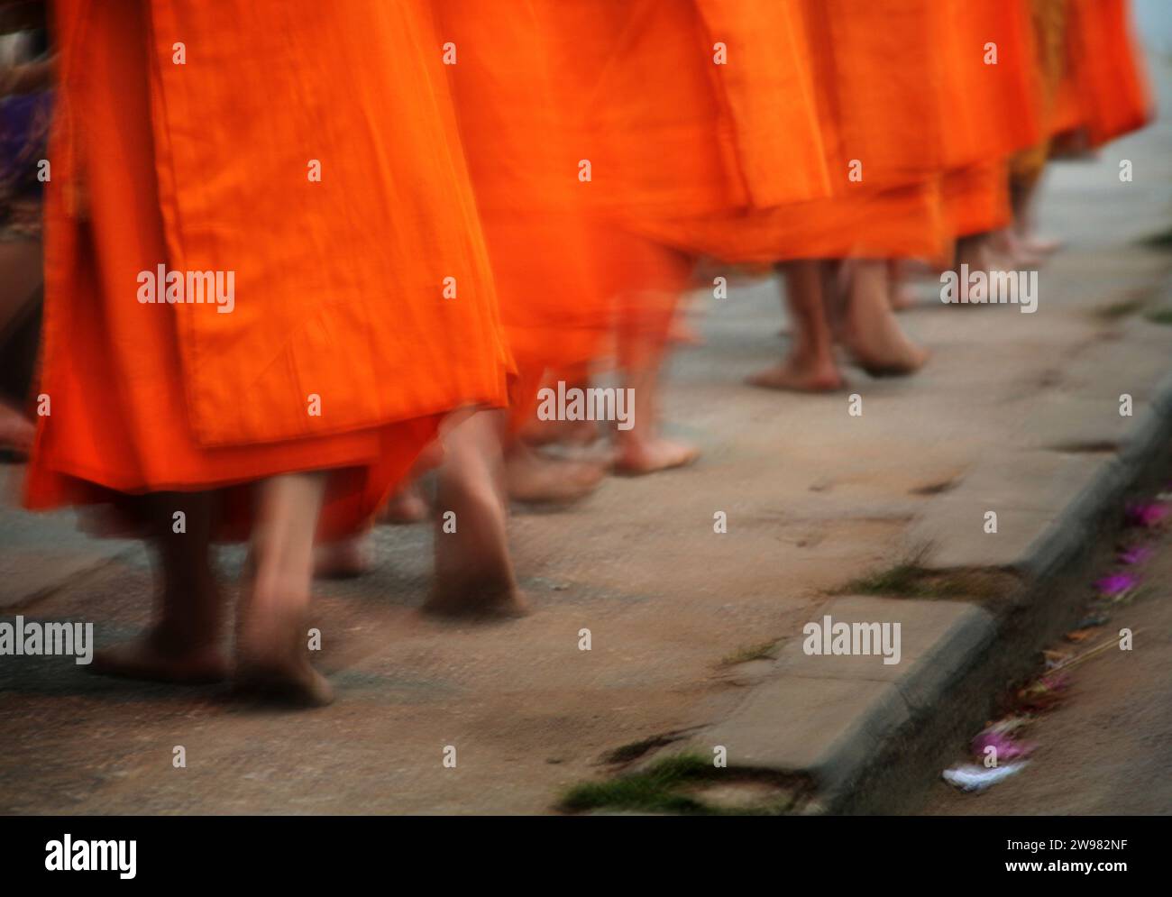Buddhistische Mönchfüße gehen in einer Reihe auf einem Bürgersteig. Luong Probang, Laos. Stockfoto
