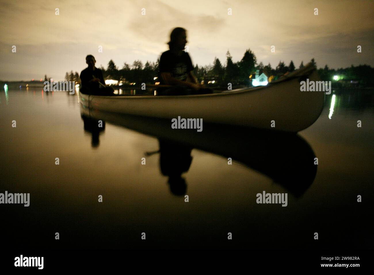 Zwei Männer sitzen nachts in den stillen Gewässern von Gig Harbor Washington. (Verschwommenes Bild). Stockfoto