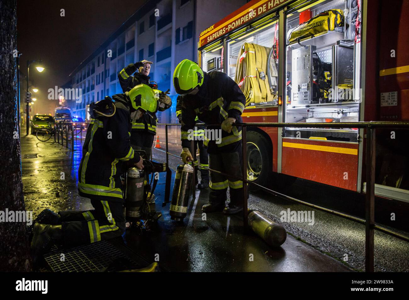 Feuerwehrmänner ändern ihre Sauerstoffflaschen nach dem Brand im Gebäude bei Nacht, Annecy, Haute-Savoie, Frankreich Stockfoto