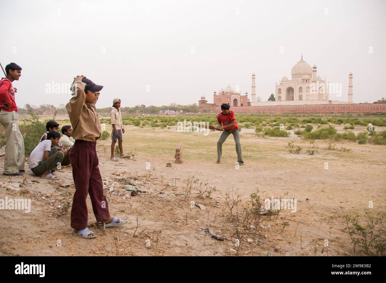 Eine Gruppe von jungen Männern und jungen ein Pick-up-Spiel Cricket mit der Taj Mahal in Agra, Indien Hintergrund. Stockfoto